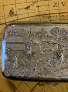 Indian silver cushioned rectangular cigar case , showing Figures In A Village thene .with buildings , trees and houses
