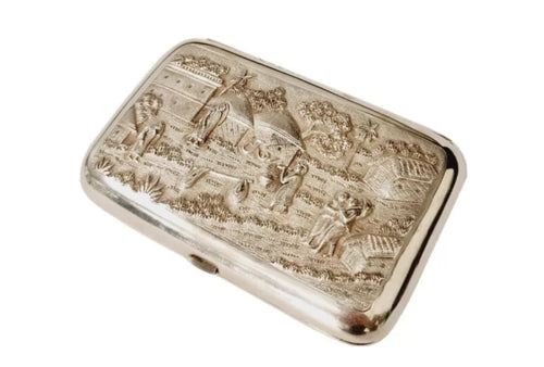 Indian silver cushioned rectangular cigar case , showing Figures In A Village theme with buildings , trees and houses